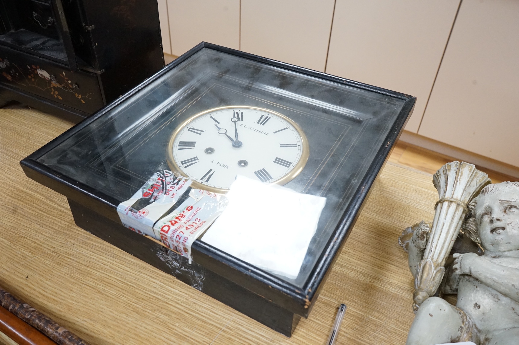 A Japanese lacquer table cabinet with inset porcelain panels, the drawers filled with sundry objects, clay pipes, decanter stoppers, etc, together with a black japanned wall clock, the dial inscribed F. L Hausburg, Paris